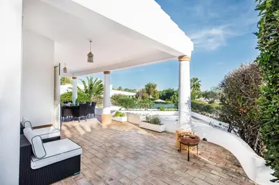 an outdoor patio with white columns and a table and chairs at Buganvilia by Algarve Villa Holidays in Guia