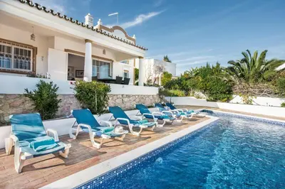 a swimming pool with blue chairs and a swimming pool at Buganvilia by Algarve Villa Holidays in Guia