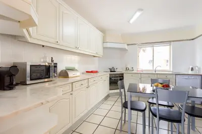 a kitchen with white cabinets and a table with chairs at Helmar by Algarve Villa Holidays in Galé
