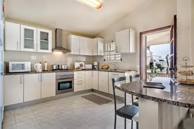 a kitchen with white cabinets and a table with chairs at Isabel by Algarve Villa Holidays in Galé