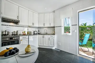 a kitchen with white cabinets and a table with fruit on it at Julieta by Algarve Villa Holidays in Galé