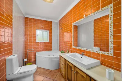 an orange tiled bathroom with a toilet and a sink at Laura by Algarve Villa Holidays in Albufeira