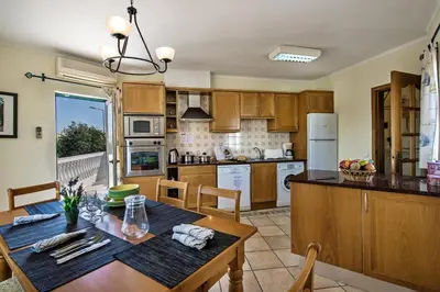 a kitchen with wooden cabinets and a table and chairs at Rebela by Algarve Villa Holidays in Galé