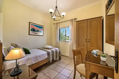 a bedroom with a bed and a desk and a chair at Rebela by Algarve Villa Holidays in Galé