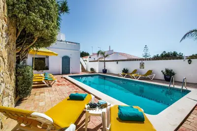 a swimming pool with yellow chairs next to a house at Rebela by Algarve Villa Holidays in Galé