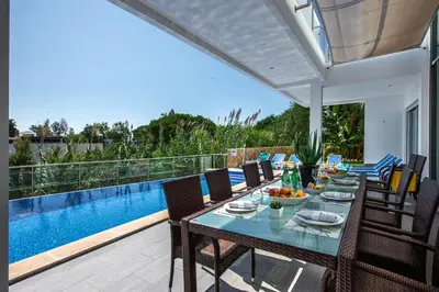a dining table and chairs on a patio with a pool at Vista Mar by Algarve Villa Holidays in Sesmarias