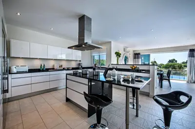 a kitchen with white cabinets and black counter chairs at Vista Mar by Algarve Villa Holidays in Sesmarias
