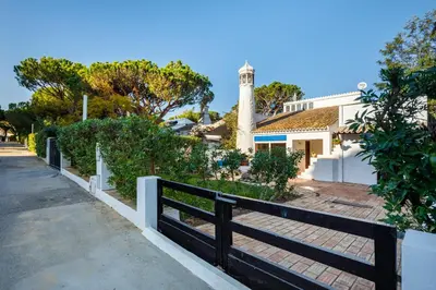 a fence in front of a house with a lighthouse at Pura Vida Falésia by The Portuguese Butler in Albufeira
