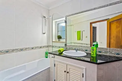 a bathroom with a sink and a tub and a mirror at Vivenda Gabriel #vivgabriel in Albufeira