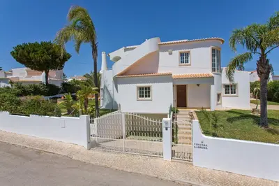 a white house with a fence and palm trees at Vivenda Gabriel #vivgabriel in Albufeira