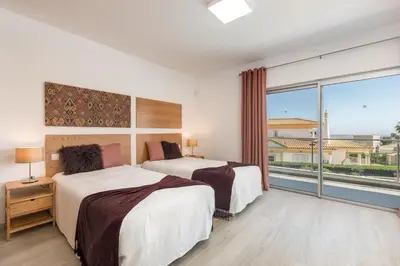 two beds in a room with a large window at Villa Alfazema - heatable pool in Albufeira