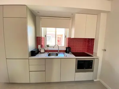 a small kitchen with white cabinets and a sink at Cardeal Suites & Apartments in Faro
