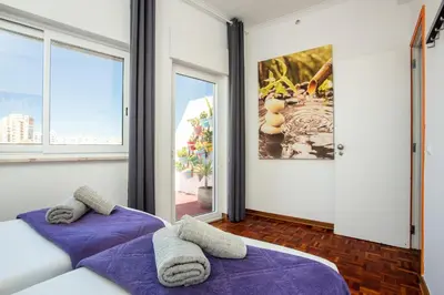 two beds in a room with two windows at Dreamers Duplex with Seaview in Faro