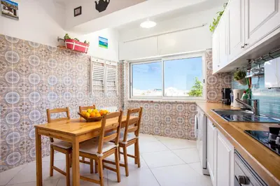 a kitchen with a wooden table and chairs and a sink at Dreamers Duplex with Seaview in Faro