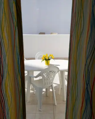 a white table with a white chair and a vase of flowers at Oura Ocean Front in Albufeira