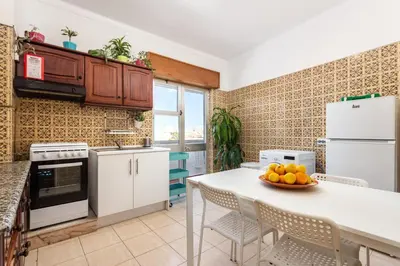 a kitchen with white appliances and a table with a bowl of fruit at Sea View Fairy Tale in Faro
