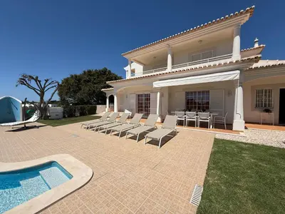 a house with chairs and a swimming pool at Casa Alves - Villa with private heated swimming pool in Olhos de Água