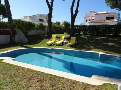 a swimming pool in a yard with chairs and a house at Vilamoura Fantástica Moradia com Piscina Privada in Vilamoura