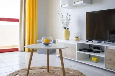 a living room with a table and a tv at Centralgarve - 1 Bedroom Apartment Near the Beach in Quarteira - Anglo Atlântico in Quarteira