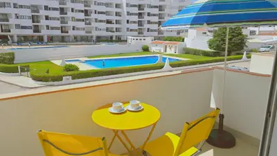 a table and chairs with a yellow table and a pool at Praia Eulália with pool and 5 minutes from the beach in Albufeira