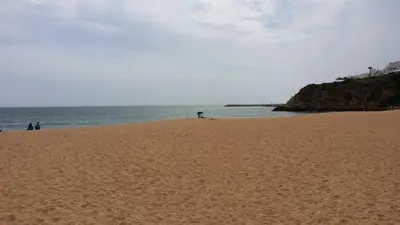 a person standing on a sandy beach near the ocean at Algarve Villa Albufeira Altos dos Caliços in Albufeira