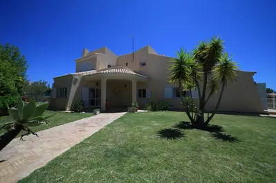 a large house with a palm tree in the yard at Casa Coral in Albufeira