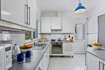 a large kitchen with white cabinets and appliances at Villa White Sands - Private Oasis, Heated Pool, Beaches & Strip Nearby in Albufeira