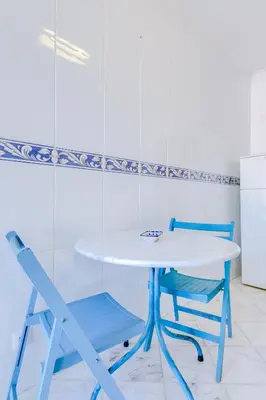 a white table and two blue chairs in a kitchen at Mango Apartment - Faro city center in Faro