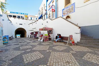 a woman sitting on a bench in front of a building at Albufeira Beach 1 by Homing in Albufeira