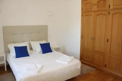 a bedroom with a white bed with blue pillows at Villa V2 Z in Olhos de Água