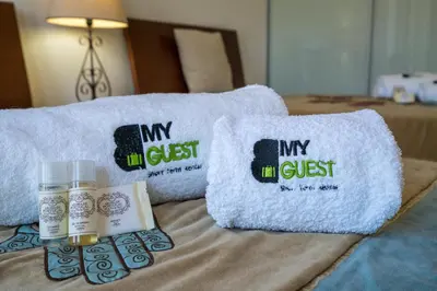 a bed with two towels and a bottle of oil and a pillow at BmyGuest - Cavalo Preto Beach Apartment in Loulé