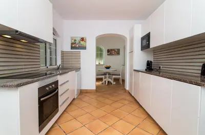 a kitchen with white cabinets and a tile floor at Albuera Villa in Albufeira