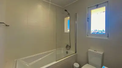 a bathroom with a shower and a toilet and a window at Penthouse Duplex Marina Plaza T1 HsR Marina Vilamoura in Vilamoura