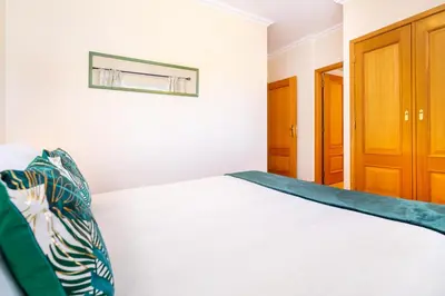 a bedroom with a white bed and a wooden cabinet at WHome | Vilamoura Family Apartment in Quarteira