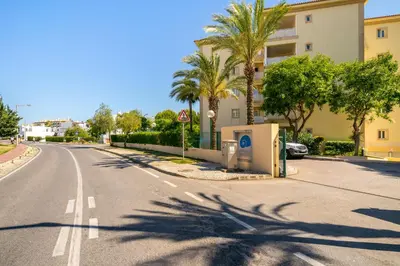 an empty street with palm trees and a building at WHome | Vilamoura Family Apartment in Quarteira