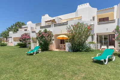 a large white house with chairs and an umbrella at FLH Balaia Village Apartment with Pool I in Olhos de Água