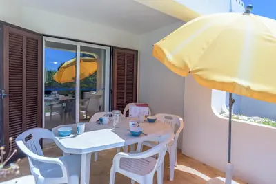 a table with a yellow umbrella and a table and chairs at FLH Balaia Village Apartment with Pool II in Olhos de Água