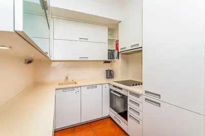 a kitchen with white cabinets and an orange tile floor at Onde a Marina é Casa T2 HsR Vilamarina in Vilamoura