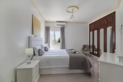 a white bedroom with a large bed and a window at Villa Santo Estevão in Olhos de Água