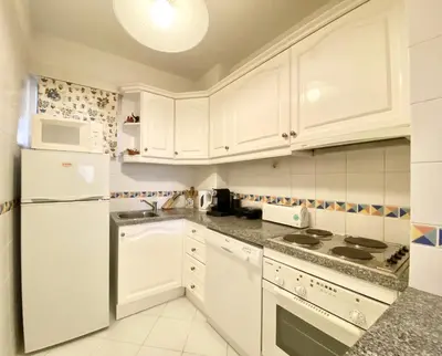 a white kitchen with white cabinets and appliances at Marina Mar - Near the beach - Vilamoura in Vilamoura