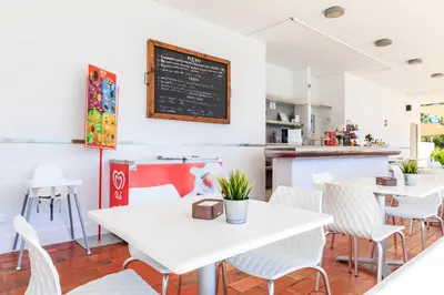 a restaurant with white tables and chairs and a chalkboard at Victory Village T1 & Rooftop terrace in Quinta do Lago