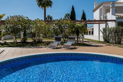two chairs and a swimming pool in front of a house at Villa Cantinho by Intiholidays in Albufeira