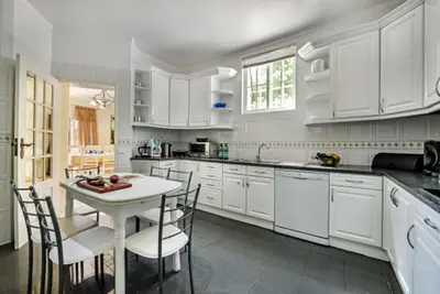 a kitchen with white cabinets and a table and chairs at Forte São João Villas da Praia in Albufeira