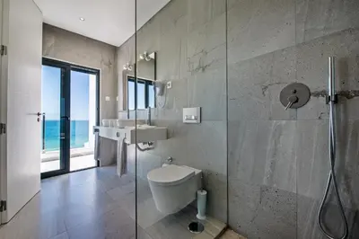 a bathroom with a toilet and a glass shower at Forte São João Villas da Praia in Albufeira