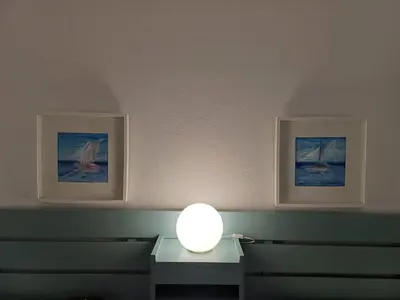 a lamp on a table in a room with two pictures at A dois passos da praia in Albufeira