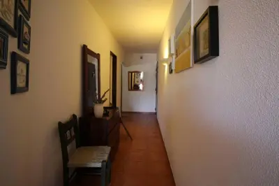 a hallway with a chair and pictures on the wall at A dois passos da praia in Albufeira