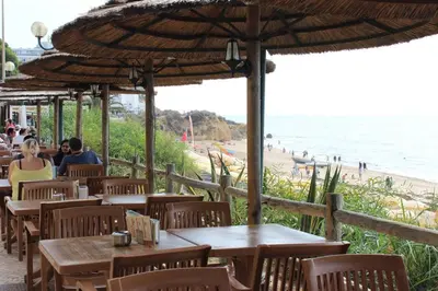 a restaurant with tables and chairs and a beach at A dois passos da praia in Albufeira