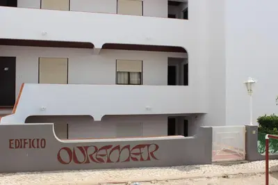 a white building with red writing on the side of it at A dois passos da praia in Albufeira