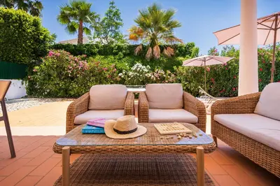 a patio with two chairs and a table with a hat on it at Villa Ericeira by OCvillas in Albufeira