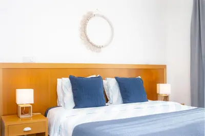 a bed with blue and white sheets and a mirror at Bay View by OCvillas in Albufeira
